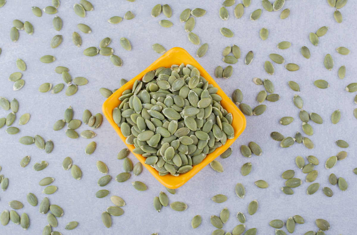 Raw pepitas in and scattered around a bowl on marble background. High quality photo